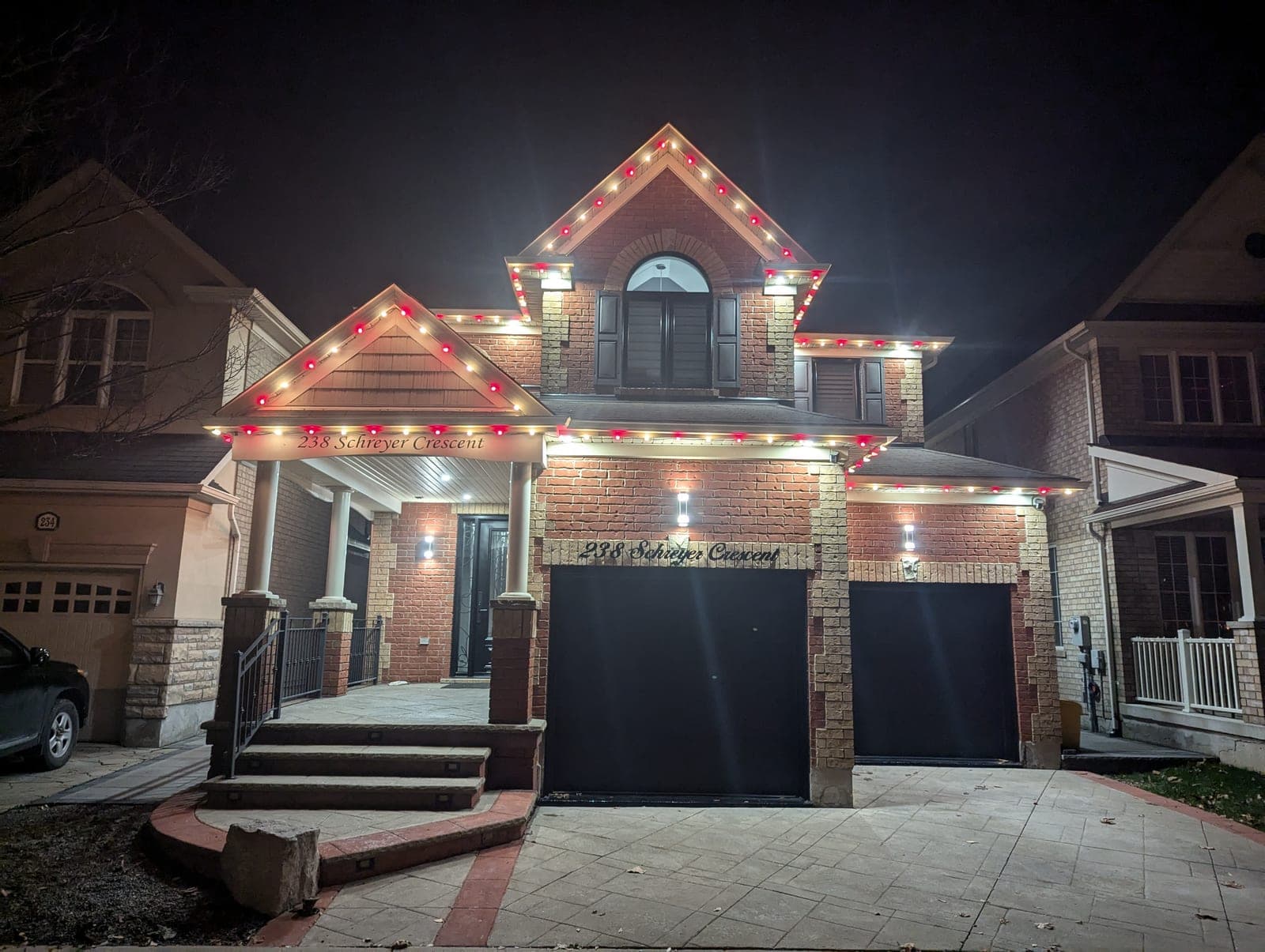 Brick home with red-accented warm-white C9 Christmas lights tracing the roof peaks and gables