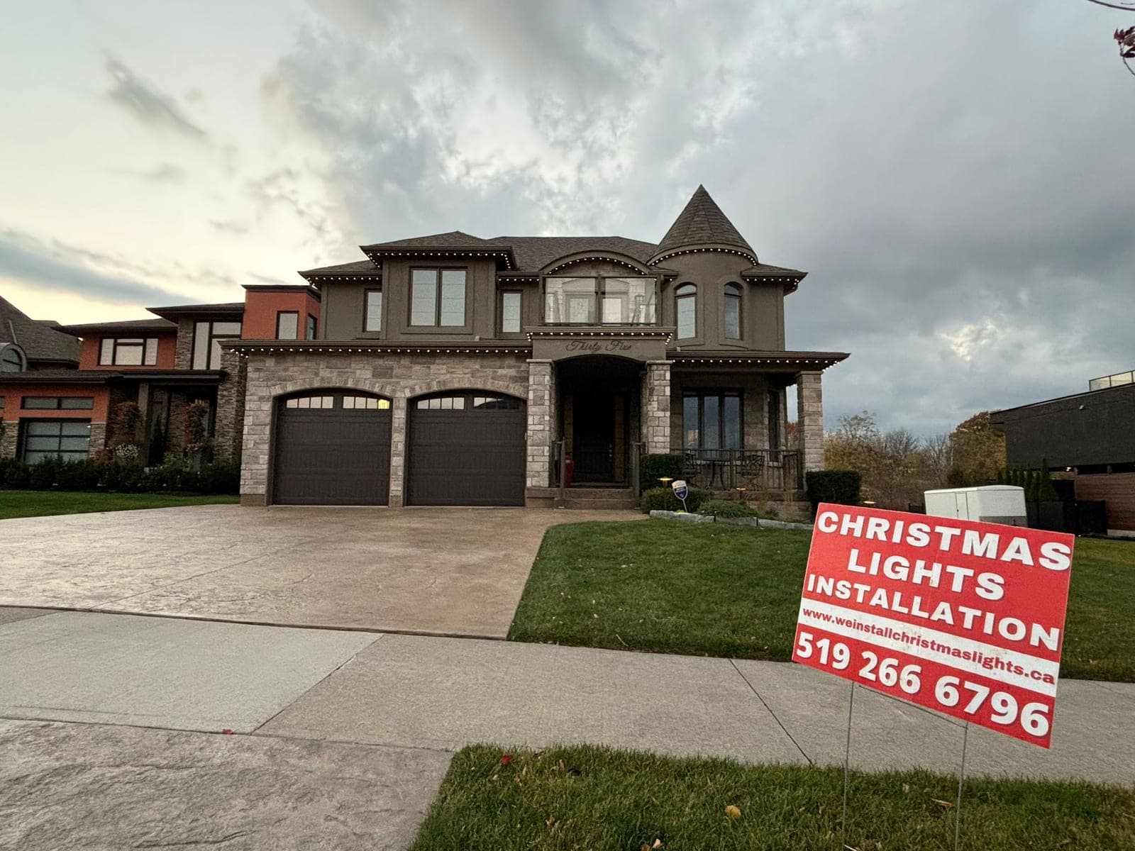 Warm-white C9 Christmas lights professionally installed along the rooflines of a large two-storey home