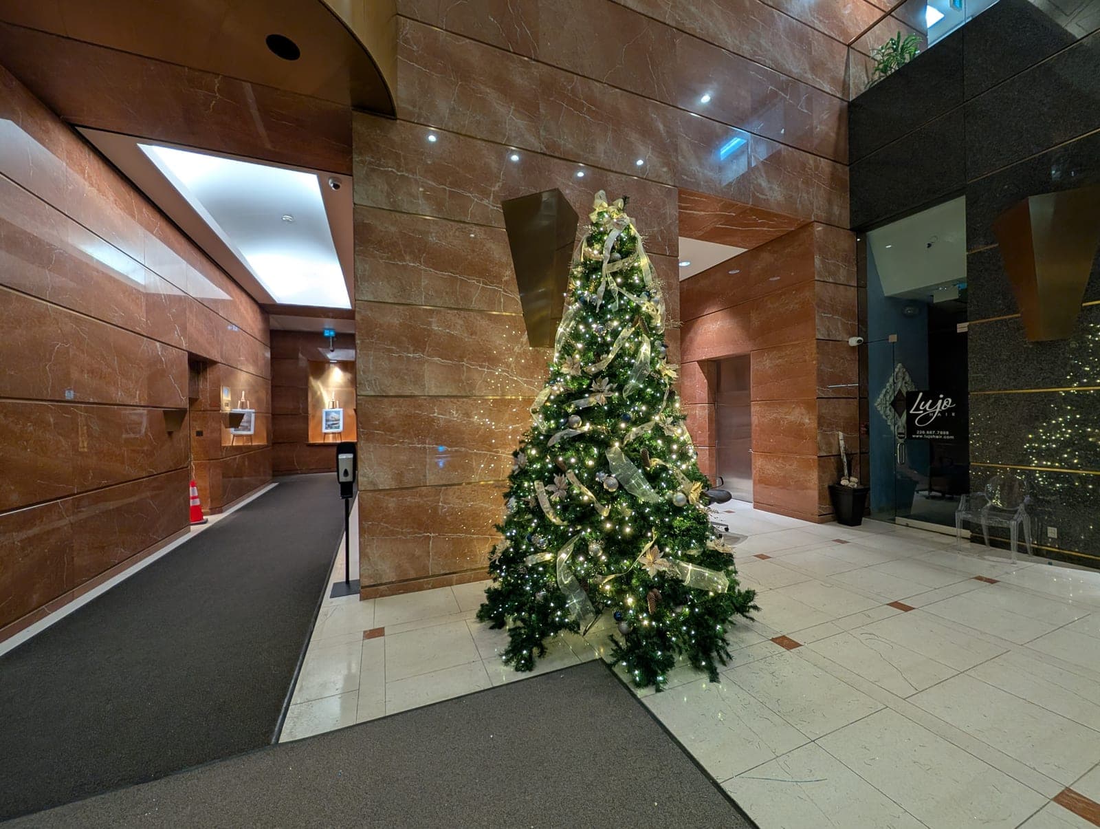 Christmas tree with gold ribbon in a spacious commercial marble lobby with warm-white lighting