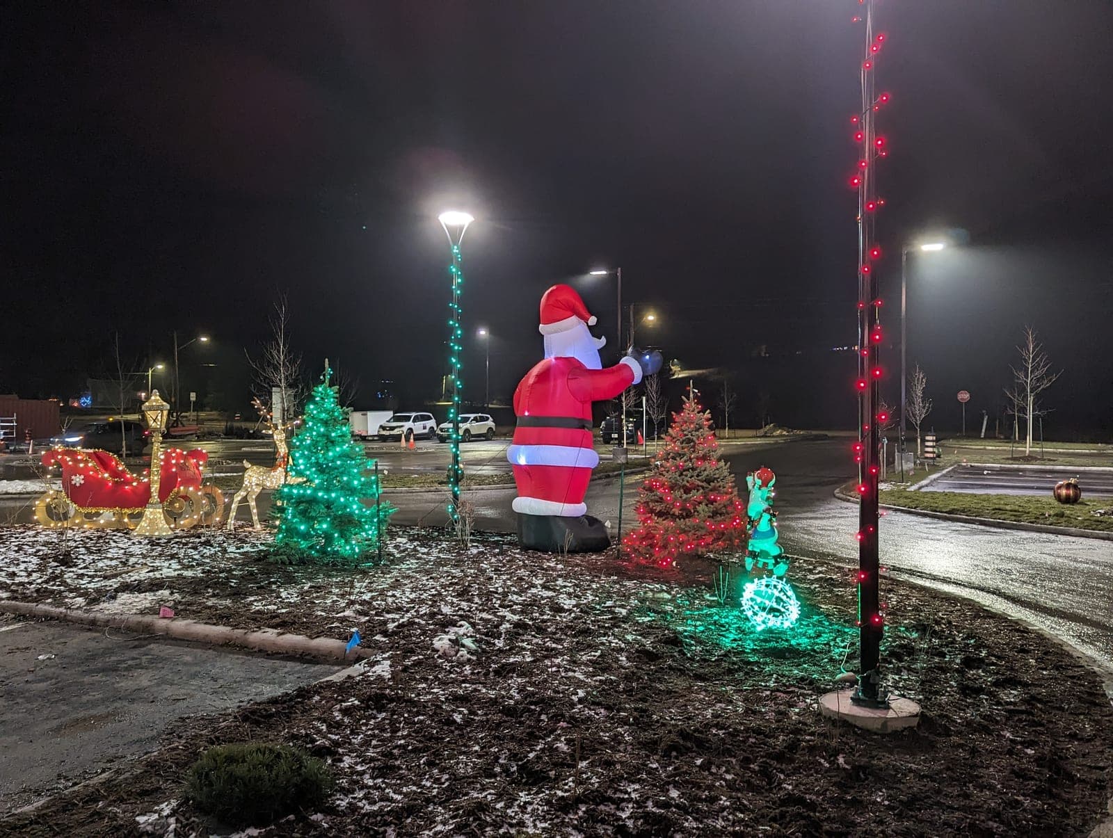 Giant lit inflatable Santa with a sleigh and reindeer holiday display in a commercial courtyard
