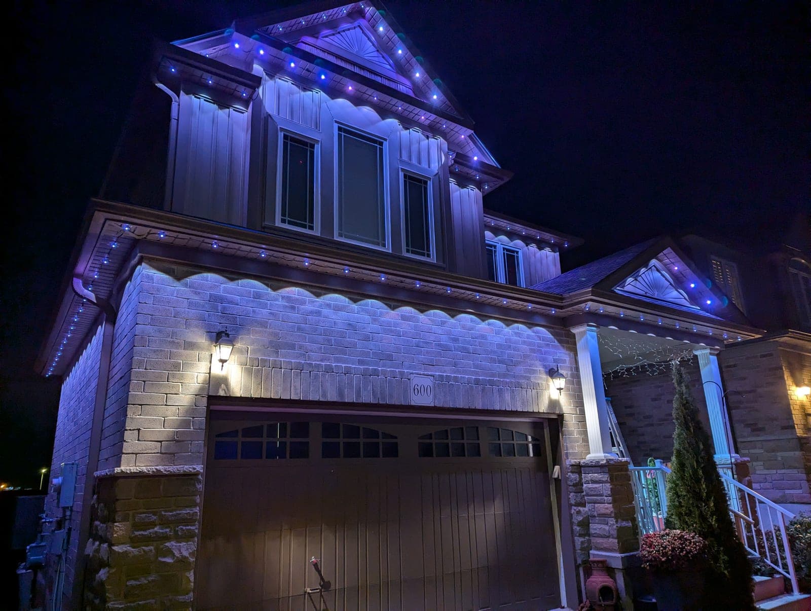Home trimmed with blue permanent LED eave and icicle Christmas lighting at night