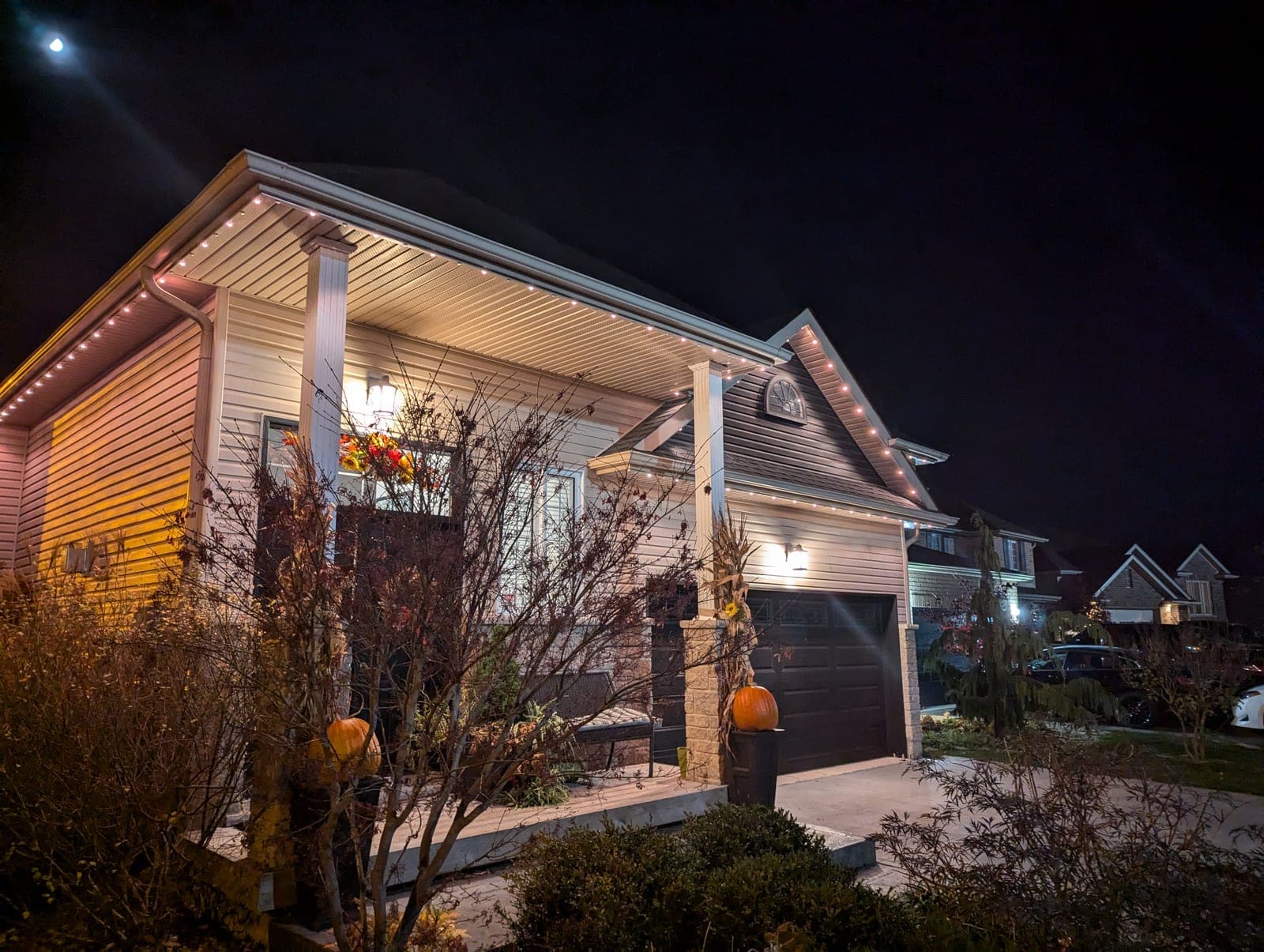 Home with warm-white permanent roofline lighting glowing across the porch and gables