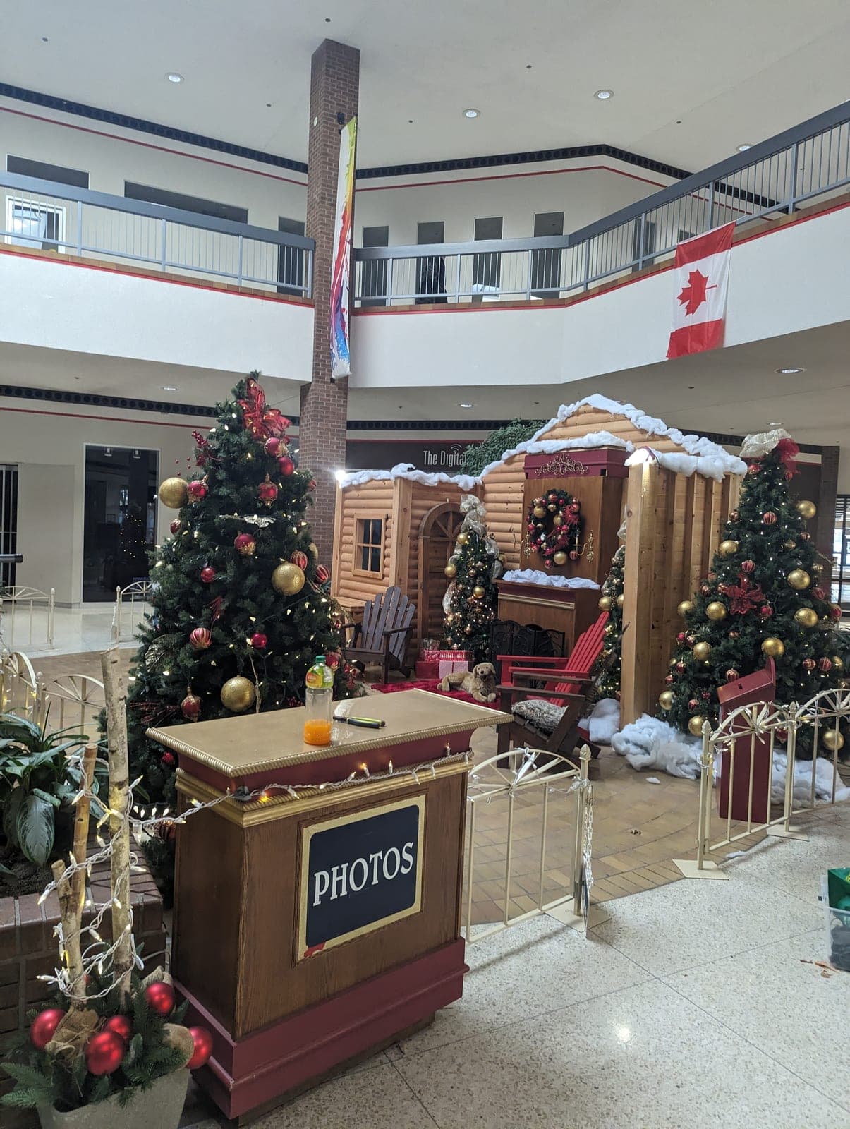 Mall Santa photo set with a log cabin, decorated Christmas trees and a PHOTOS podium in the atrium