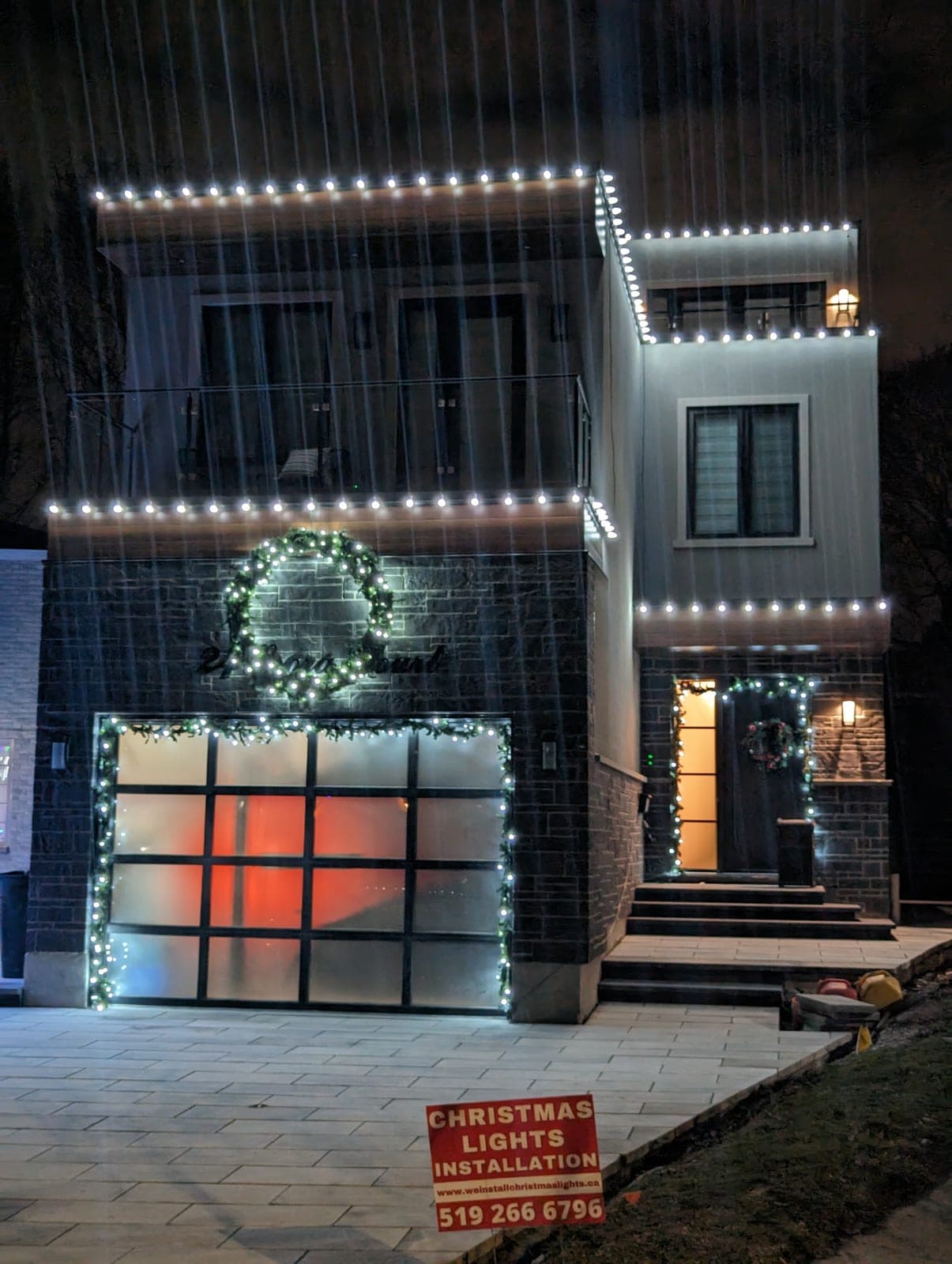 Modern two-storey home outlined in warm-white roofline Christmas lights on a winter night