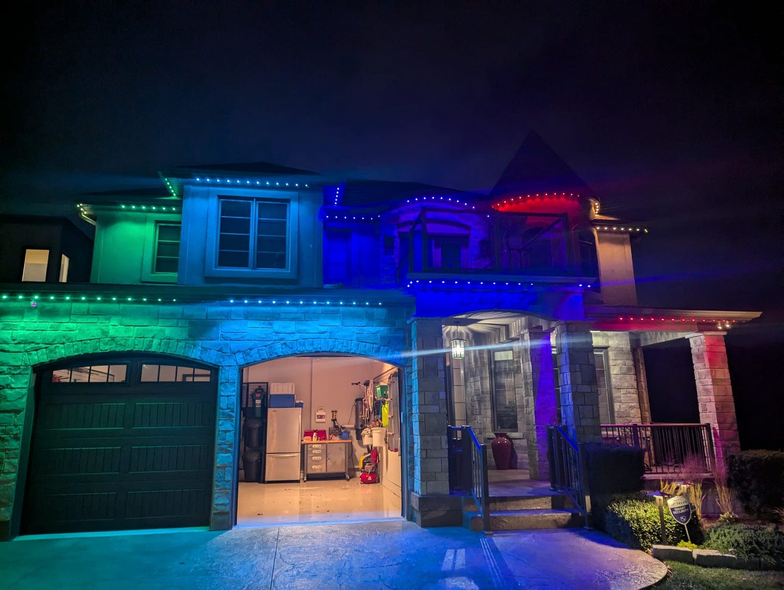 Two-storey home outlined in green, blue and red RGB permanent LED roofline lighting at night